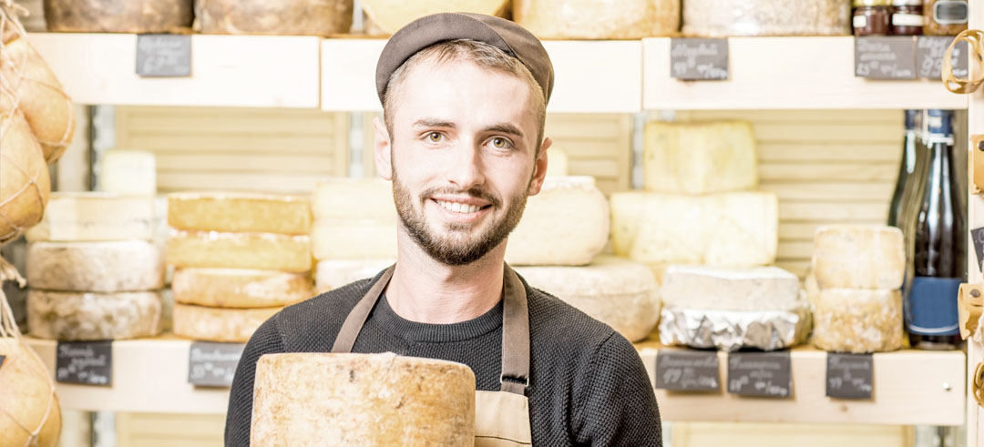Trabajador con un queso entre las manos en un local comercial